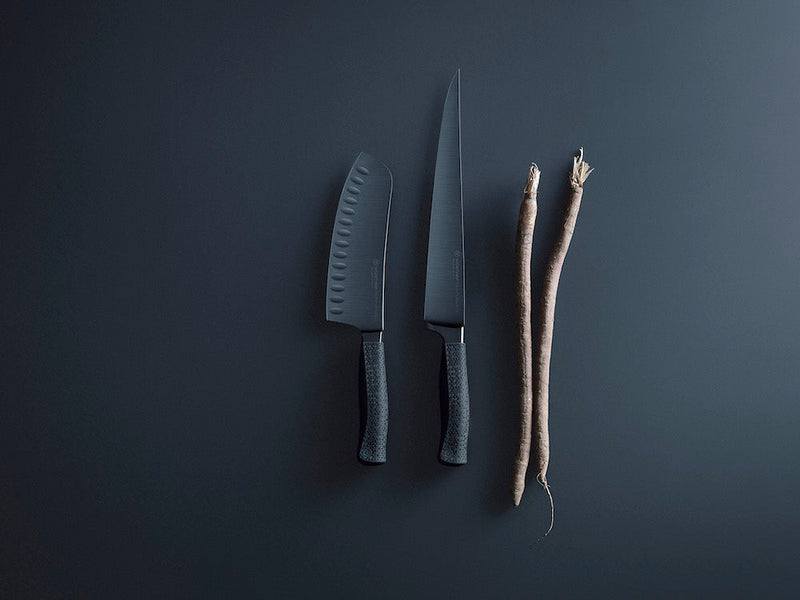Two knives and a root on a dark gray background