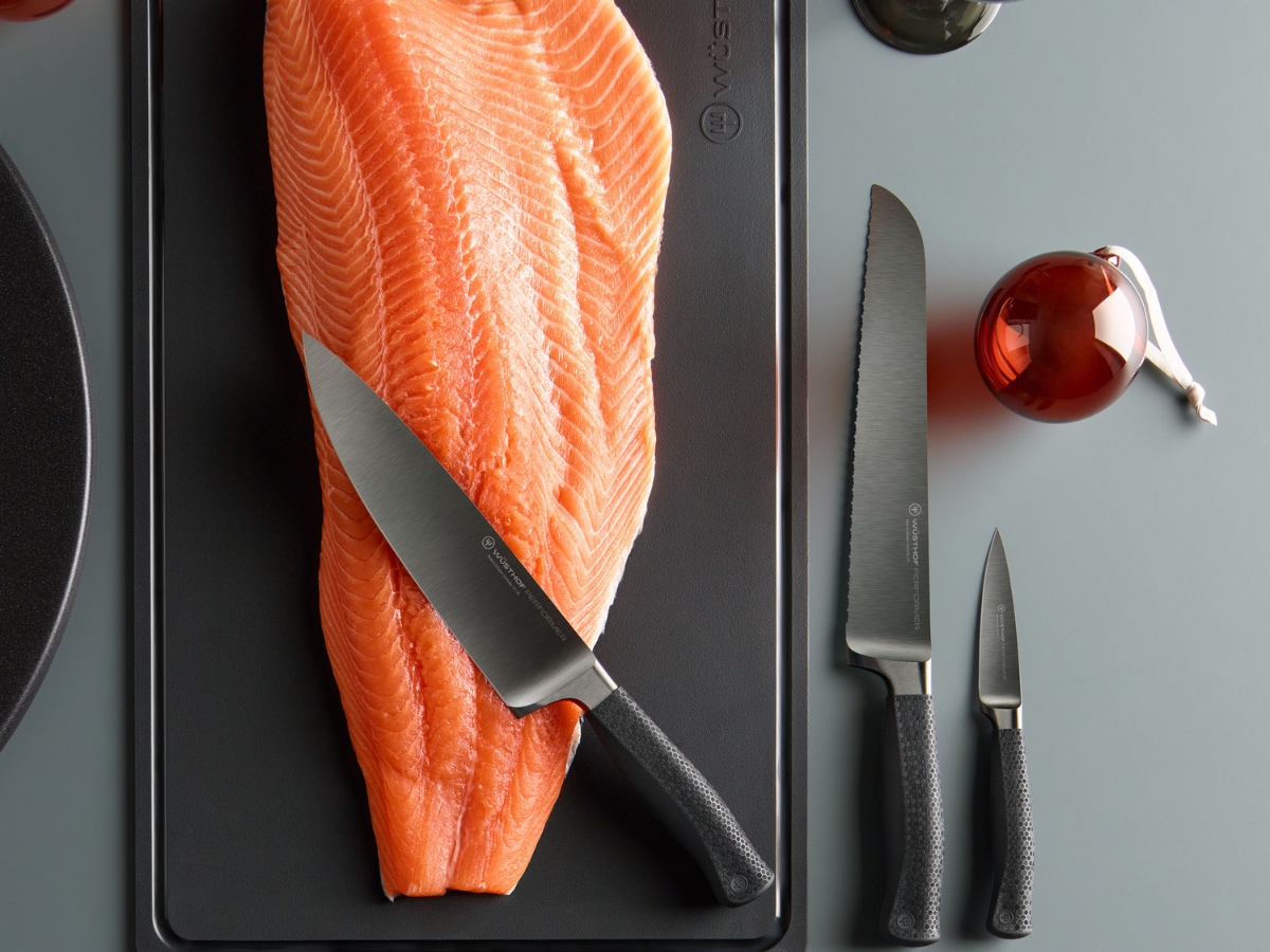 Performer knives on slab of salmon near ornate cup