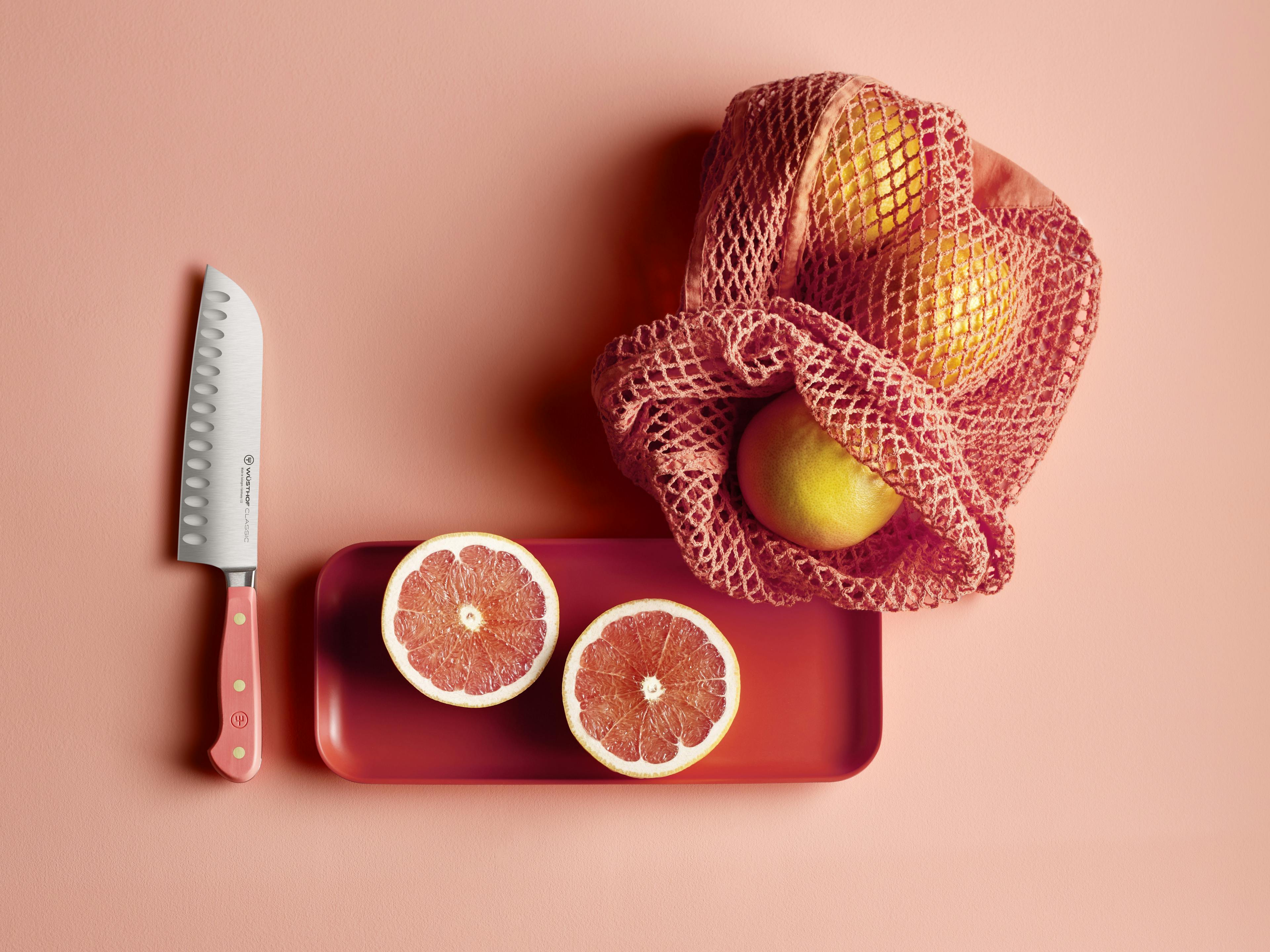 Coral peach hollow edge santoku near vibrant fruit and netted bag