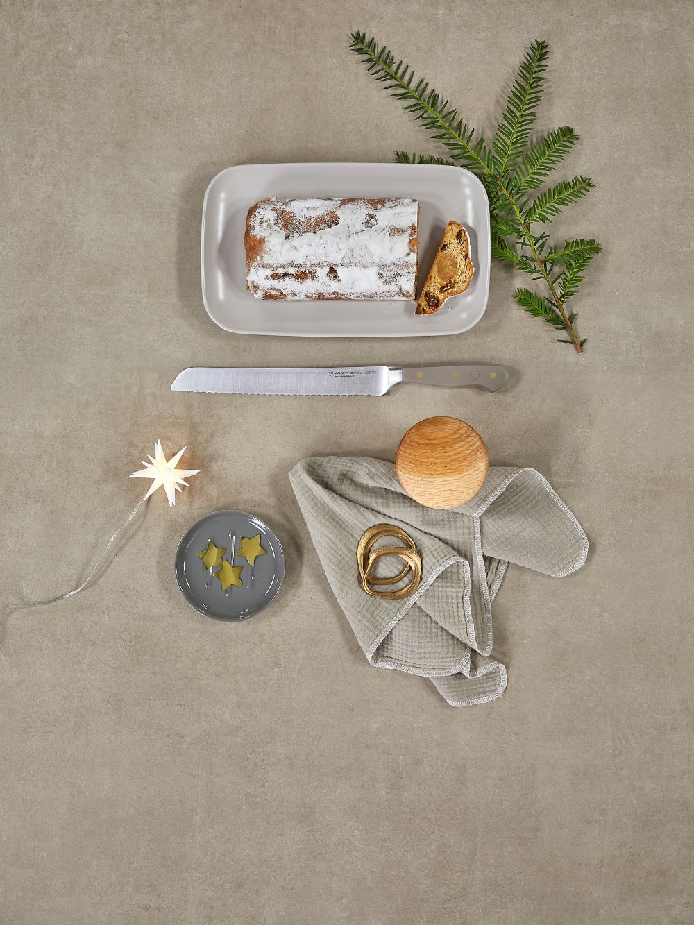 Rectangular plate with a dessert, a knife, a small star-shaped light, and a decorative branch on a beige surface.