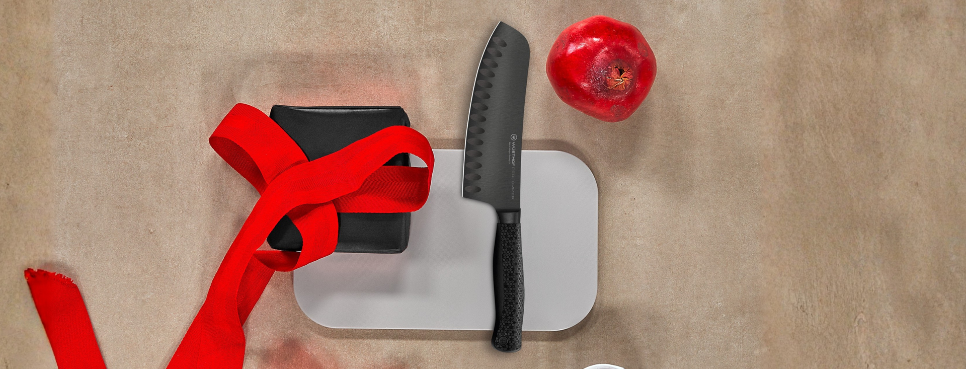 Knife on brown white cutting board with pomegranate.