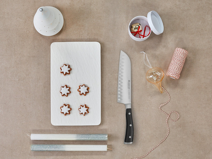 Decorative cookies on a white board with a knife, string, and small container on a beige surface
